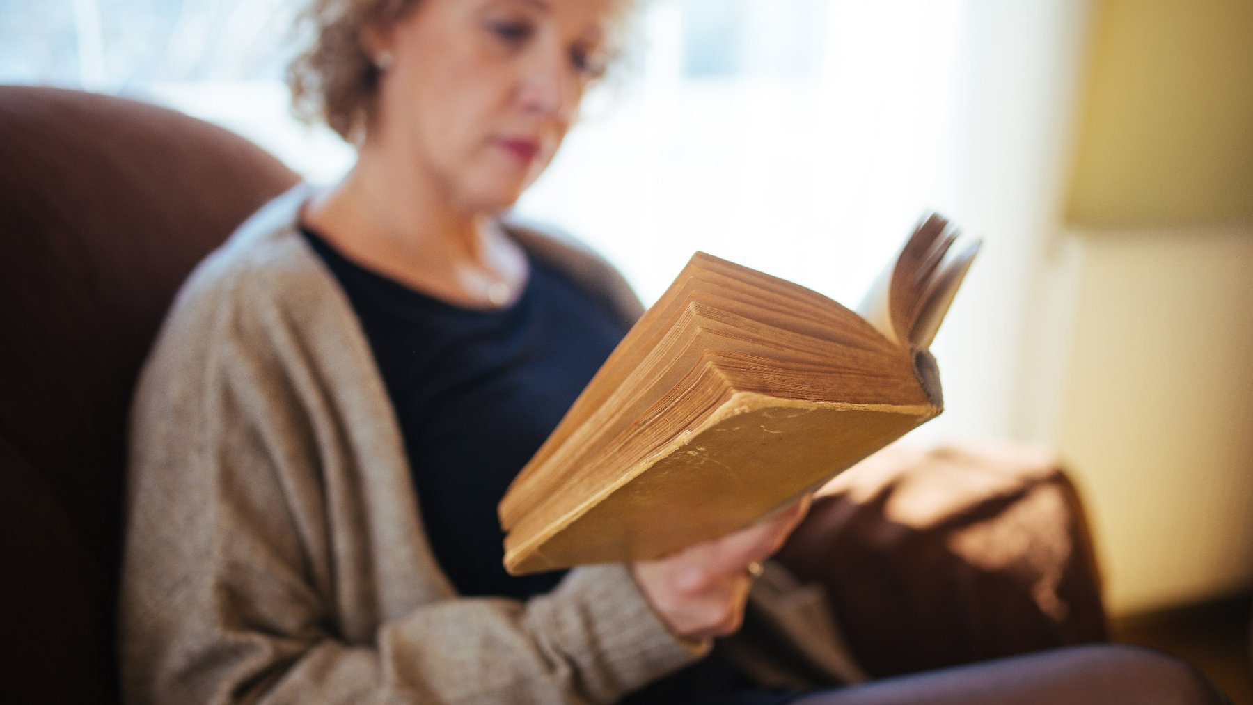 Woman reading a book in an armchair