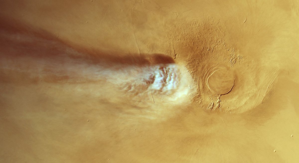 Arsia Mons volcano with a long white water-ice cloud and its shadow trailing west, seen from above