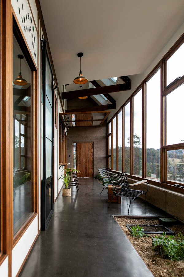 Glass sunroom of the Cygnet Earthship with a concrete floor, pendant lights and a planting bed
