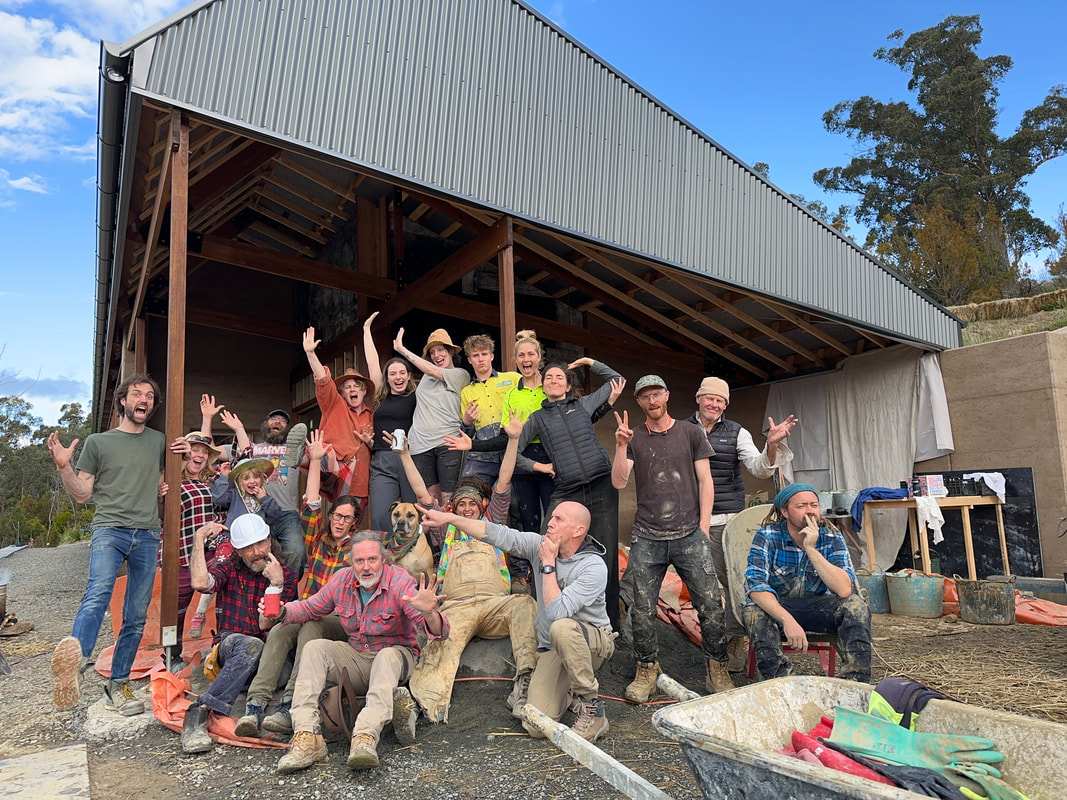 Workshop volunteers posing under the roof frame of the Cygnet Earthship during construction