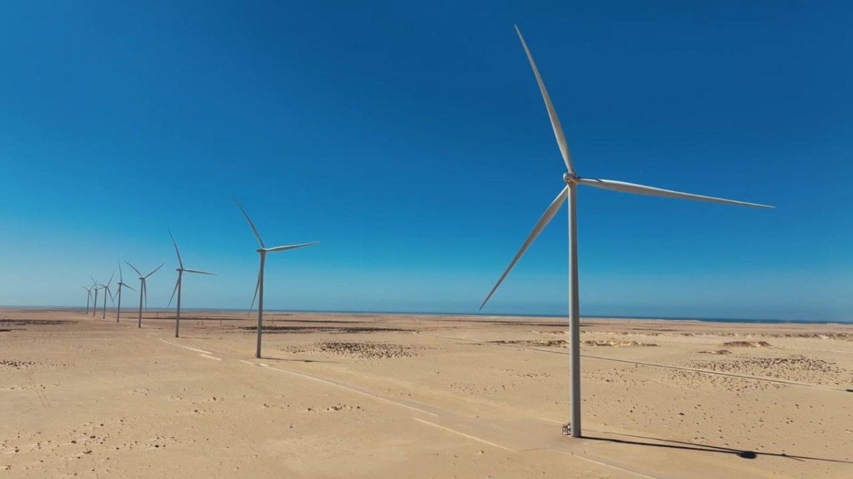 Row of white wind turbines standing on flat desert sand near the Atlantic coast at the Dakhla wind farm in Morocco
