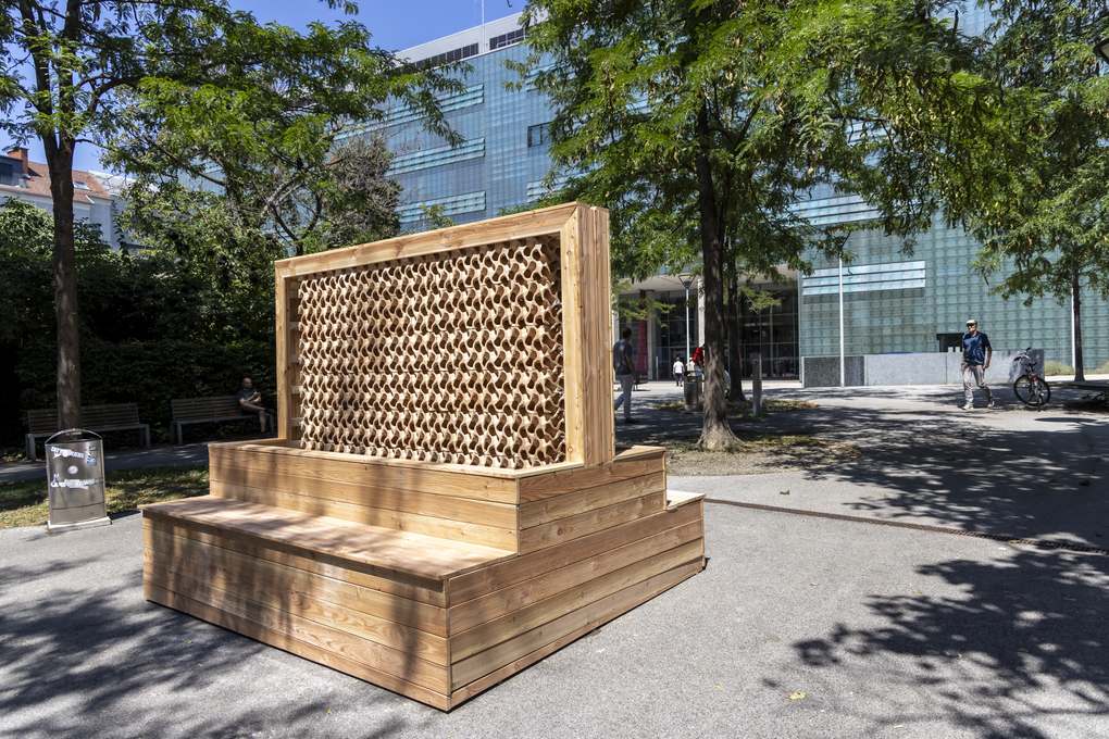 Free-standing ceramic cooling wall of clay cubes in a wooden frame with a bench on the TU Graz Neue Technik campus