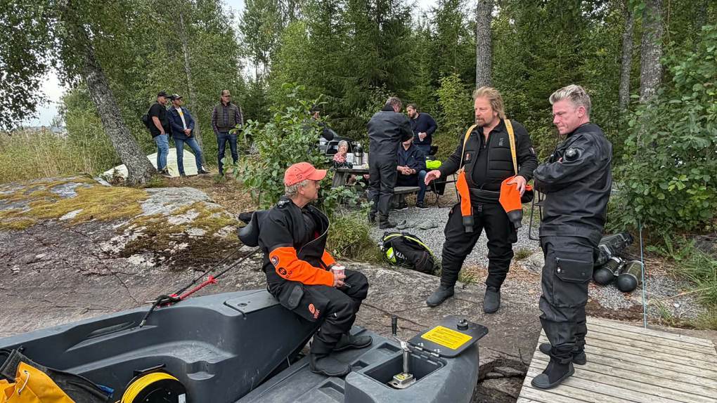Divers in drysuits talking on the rocky shore of Lake Hugn before the dives on the Kantinen wreck