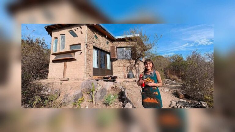 Mariana Di Pascuale in front of the earthen house she built in Los Hornillos, Traslasierra, with salvaged car windshields set as windows