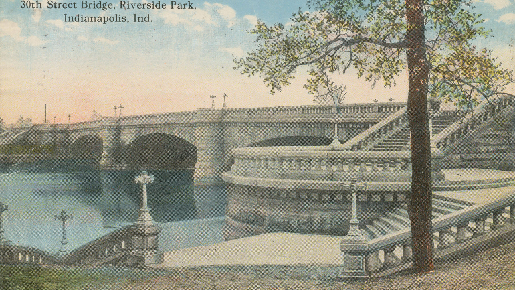 Vintage color postcard of the 30th Street Bridge in Riverside Park, Indianapolis: a stone arch bridge with grand staircases beside calm river water.