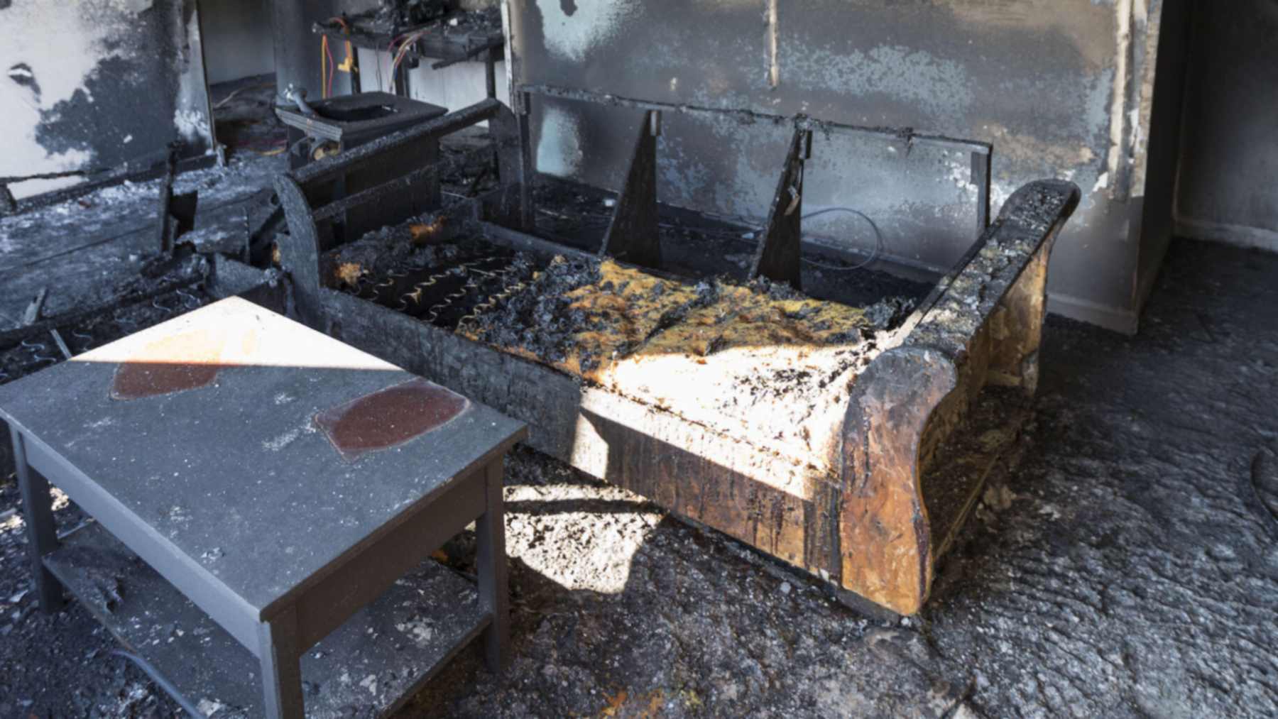 A blackened, fire-damaged room with burned furniture