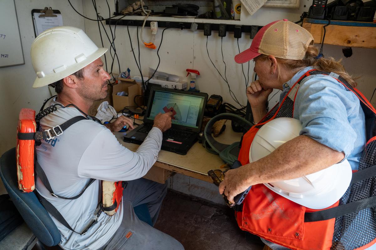 Tanner Jennings of Murtech and NOAA's Stephanie Westby look at a laptop map of the oyster reef base