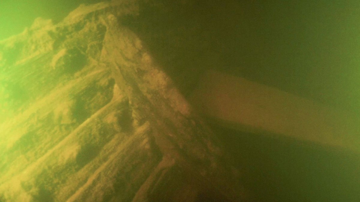 Inside of the starboard side of the Kantinen wreck, with wooden frames in green, murky water