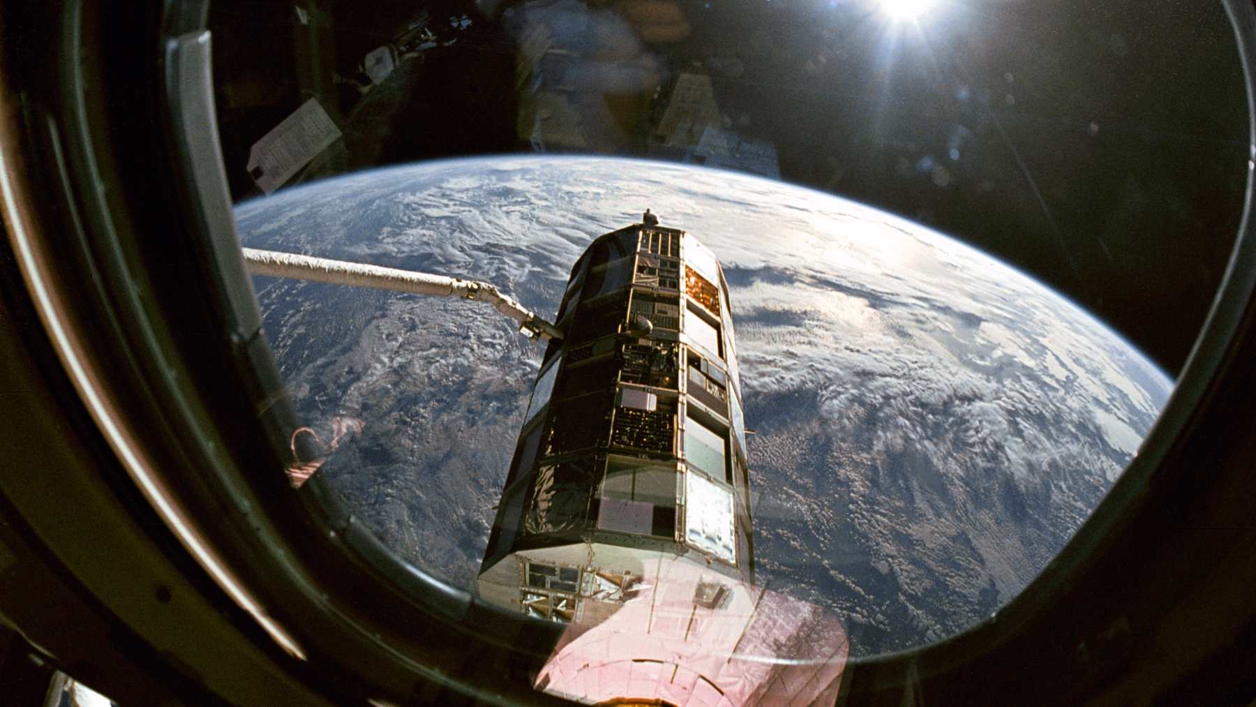 The LDEF satellite that carried the NASA tomato seeds, held by Columbia's robotic arm above Earth in January 1990