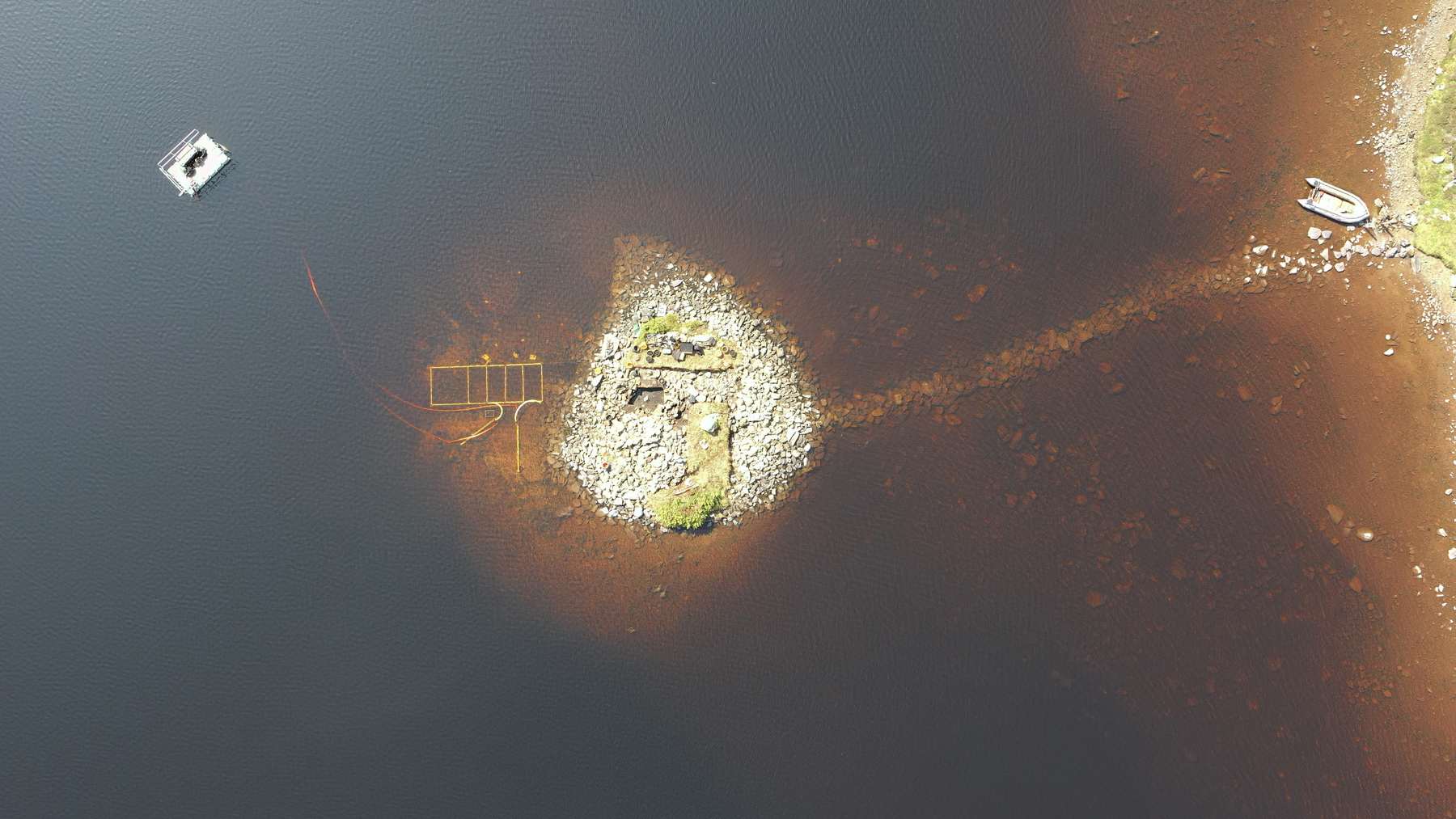 Aerial view of the 5,000-year-old artificial island in Loch Bhorgastail, with its submerged causeway and the excavation grid