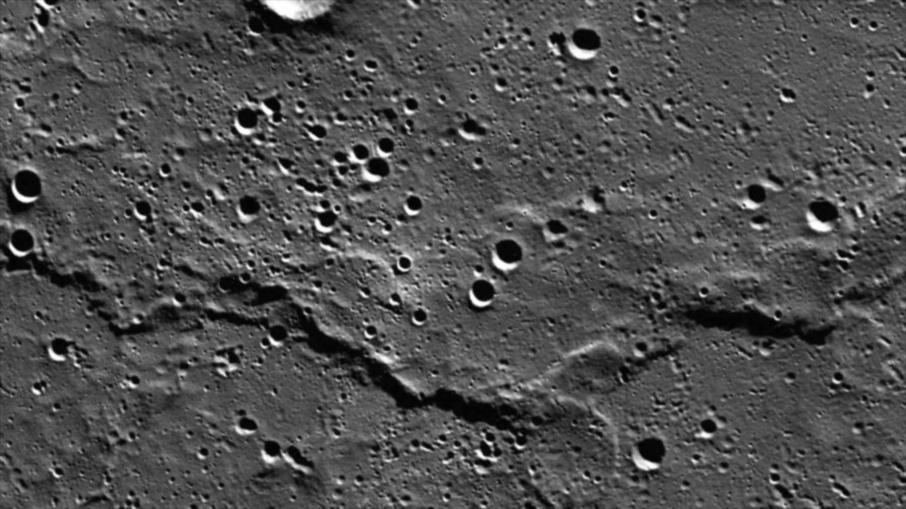 Grayscale mosaic of a long wrinkle ridge crossing cratered volcanic plains on Mercury