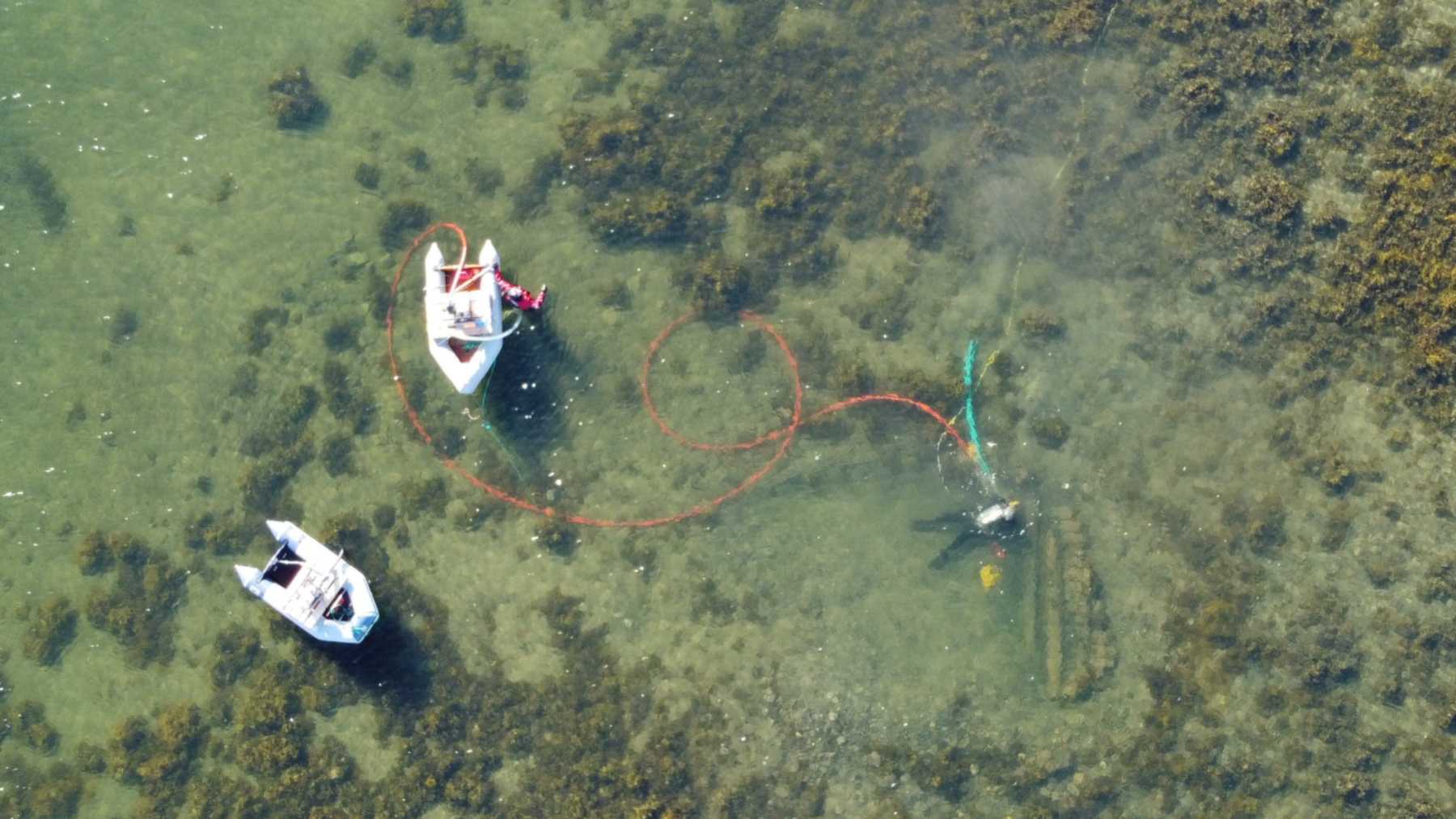 Drone view of the Mjønes shipwreck excavation in Nordland, Norway, with two inflatable boats and a diver over the wreck