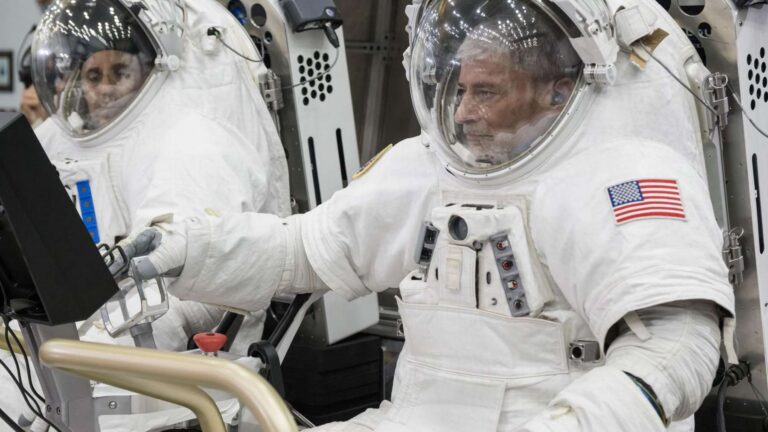 Two NASA astronauts in spacesuits sit in the Pegasus lunar terrain vehicles prototype at Johnson Space Center
