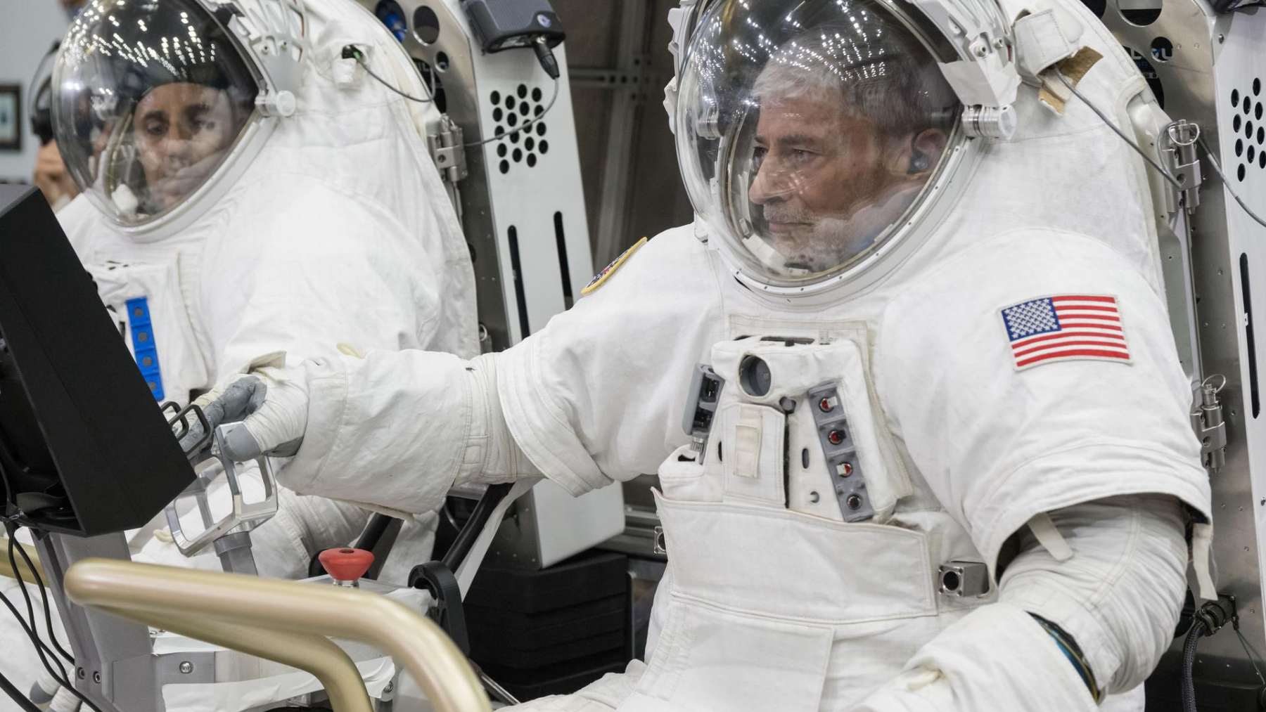 Two NASA astronauts in spacesuits sit in the Pegasus lunar terrain vehicles prototype at Johnson Space Center