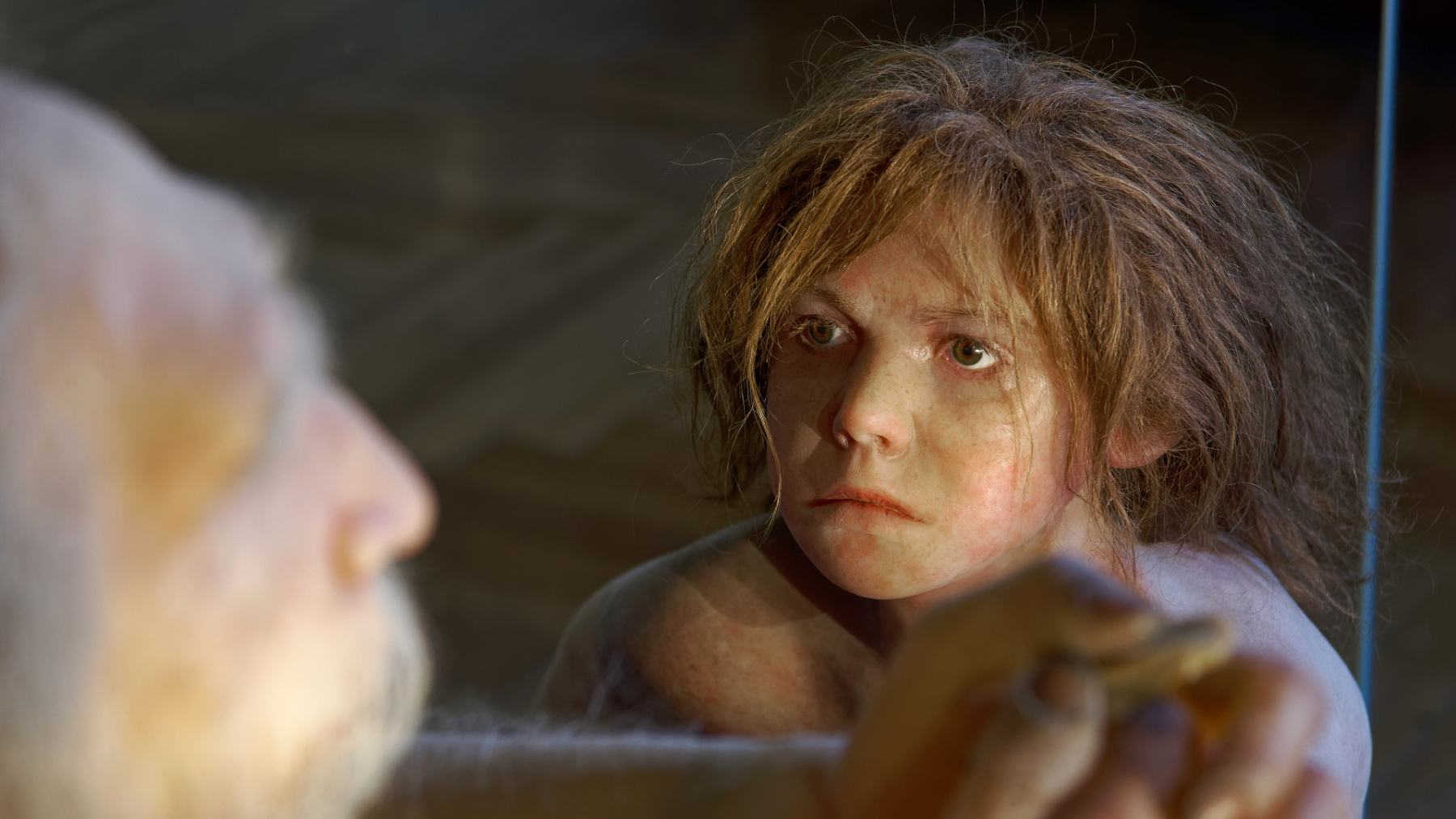 A lifelike model of a Neanderthal child with long brown hair at the Natural History Museum Vienna