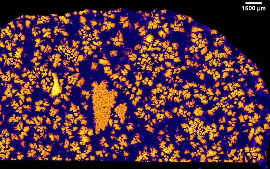 False-color X-ray map of NWA 12774 showing bright orange crystals on a dark blue background, with a 1,600-micrometer scale bar