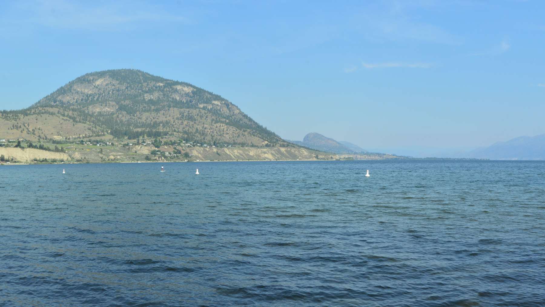 Okanagan Lake with a rounded hill on the far shore under a clear sky