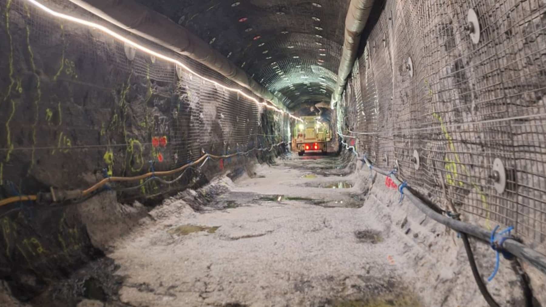 Underground tunnel at Onkalo in Finland, with reinforced rock walls, utility lines, and a construction vehicle.