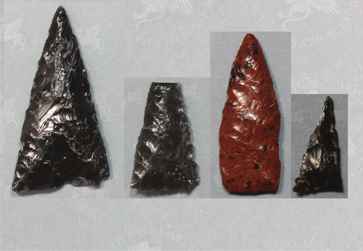 Four flaked stone projectile points, three black and one reddish, photographed side by side