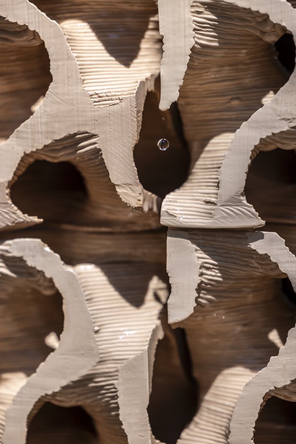 Close-up of the porous 3D-printed clay cubes of the ceramic cooling wall with a drop of water