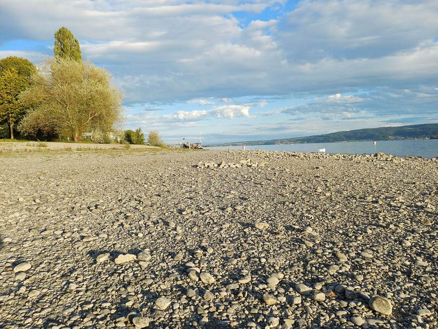 Bare pebble shore at the Strandbad Mettnau beach in Radolfzell during low water on Lake Constance