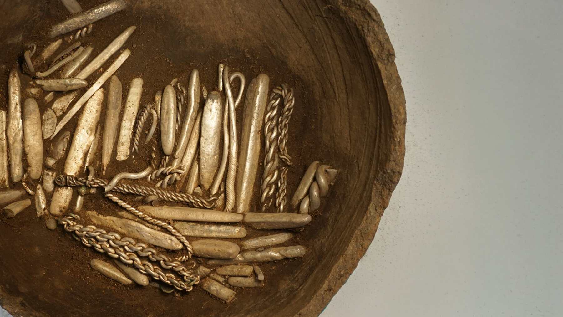 Silver bars, rings and cut silver packed inside an old clay pot