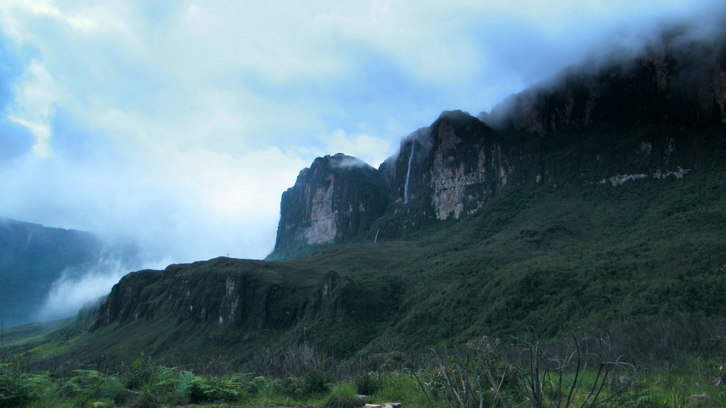 A thin waterfall pouring down the cloud-capped cliffs of Mount Roraima after rain