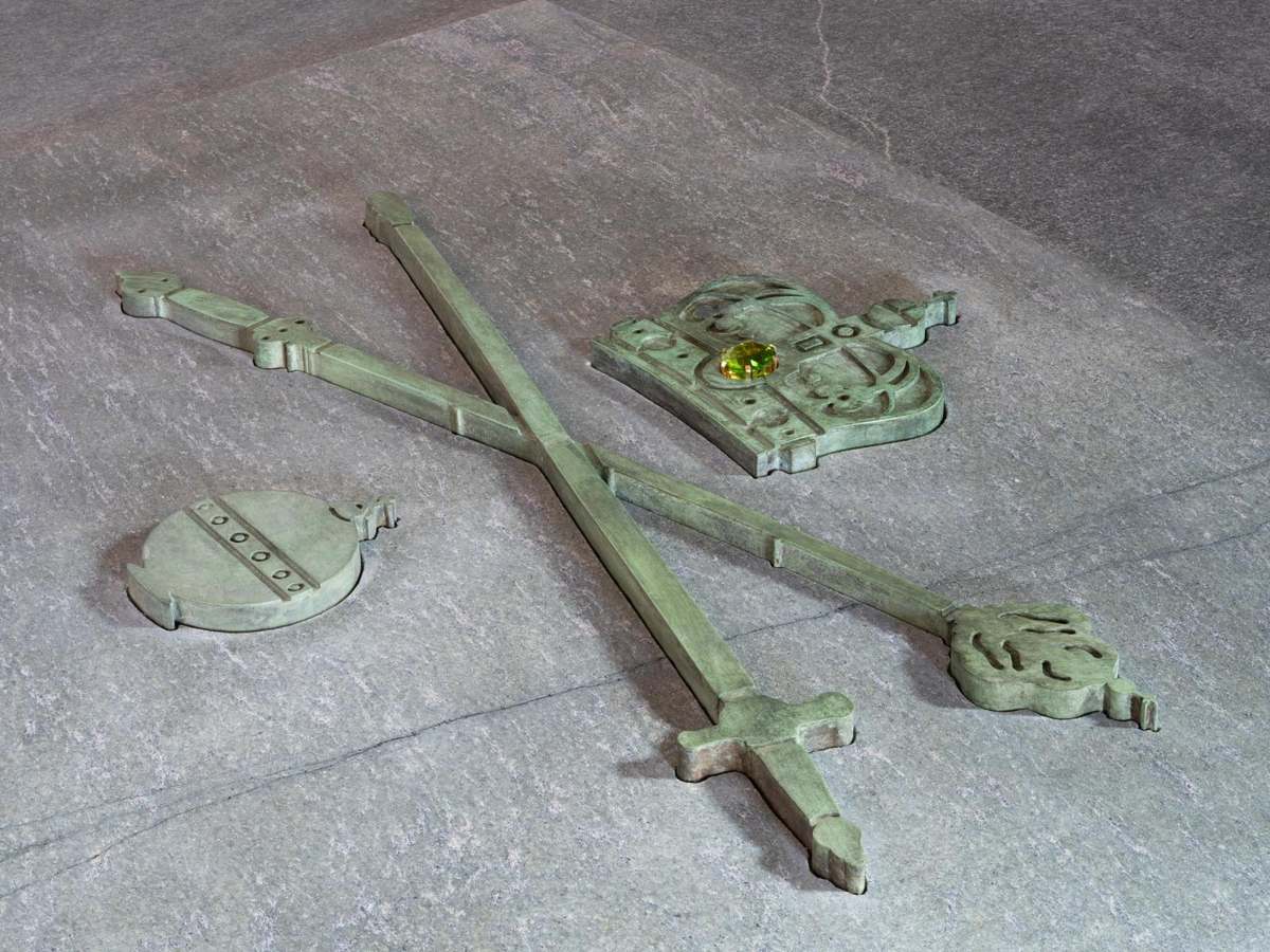 Bronze crown, orb, scepter and sword set into the gray-green stone lid of a sarcophagus