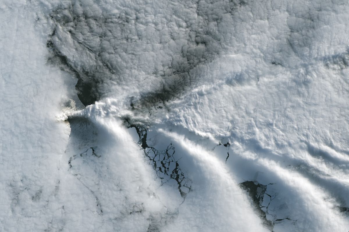 Bands of wave clouds trailing downwind of Saunders Island over sea ice, seen by Landsat 9