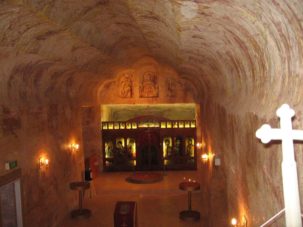 Interior of the underground Serbian Orthodox Church in Coober Pedy, with a curved rock ceiling, carved reliefs and an icon screen