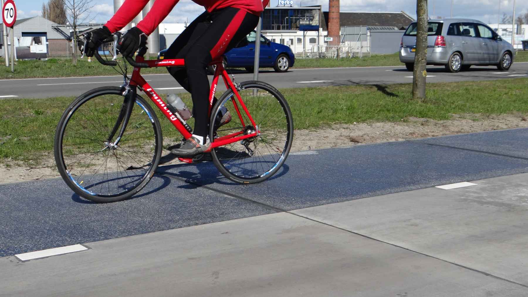 Cyclist riding over the dark solar panel lane of the SolaRoad solar bike path in Krommenie, Netherlands