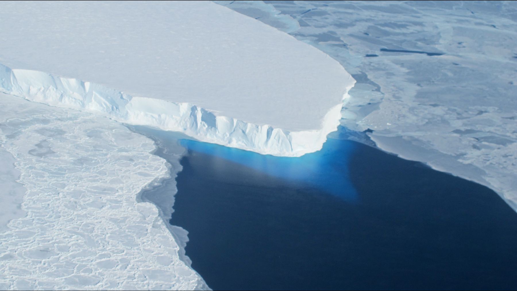 The calving front of Thwaites Glacier's ice shelf in West Antarctica above dark open water, seen from a NASA aircraft