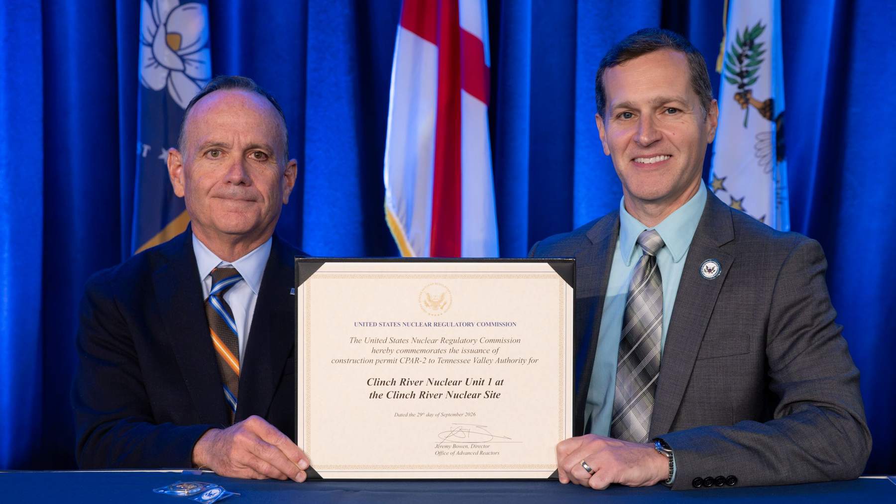 TVA's Mike Skaggs and the NRC's Jeremy Bowen hold the framed small modular reactor construction permit certificate for Clinch River Nuclear Unit 1