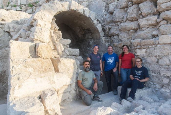 Excavation team members sitting and standing in front of the vaulted ritual bath in the Ophel, Jerusalem