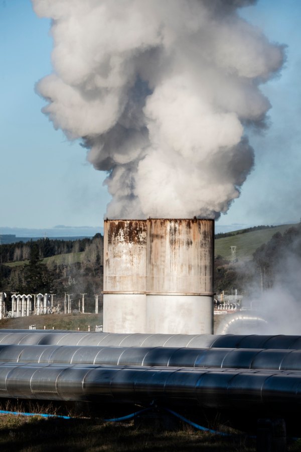 Steam rises from structures beside large pipes at the Wairakei geothermal power plant