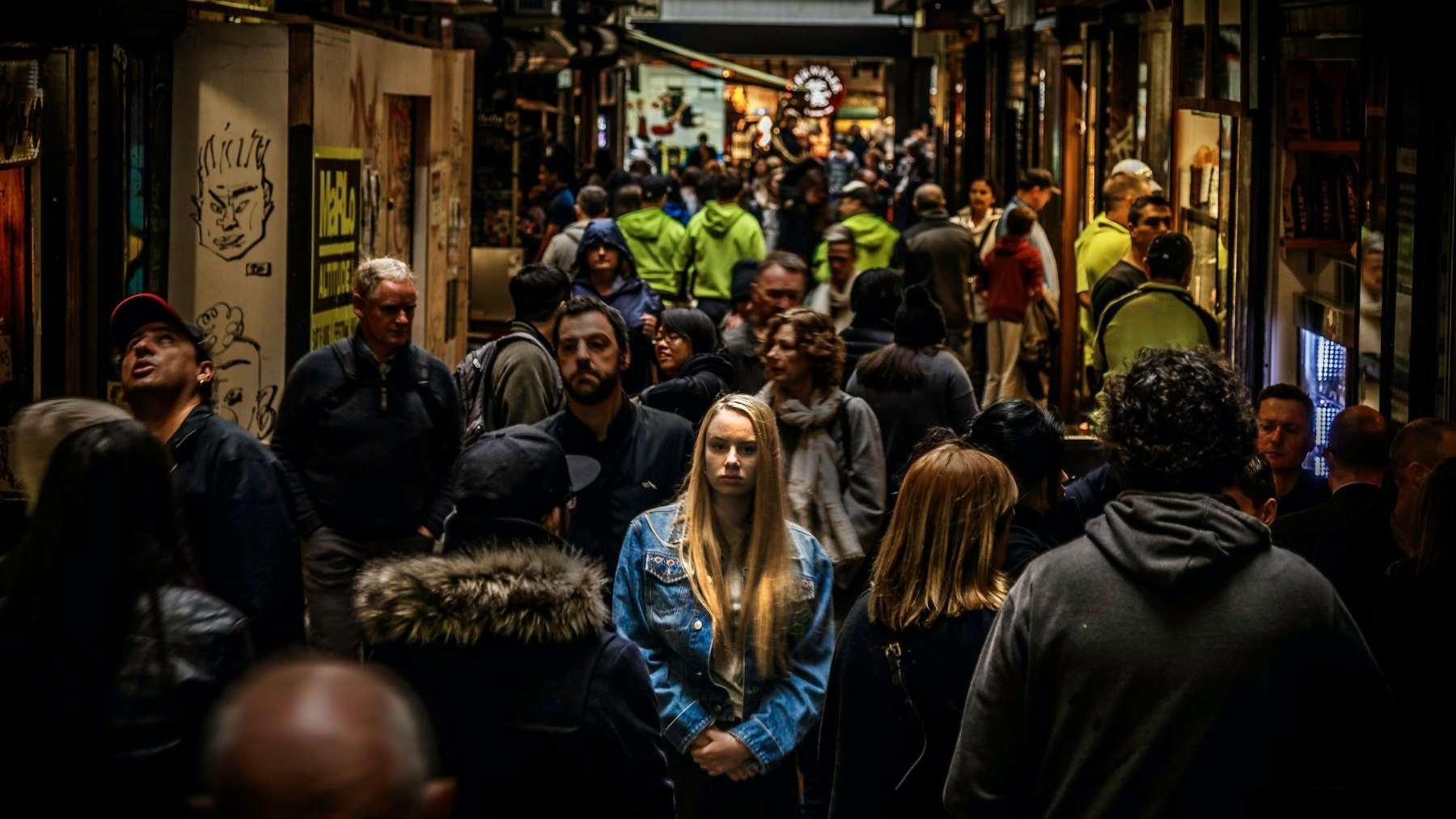 A woman standing still and looking downcast in the middle of a busy crowd