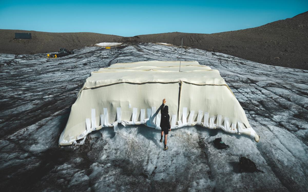 A person stands beside one of the test covers on the Glacier 3000 ice