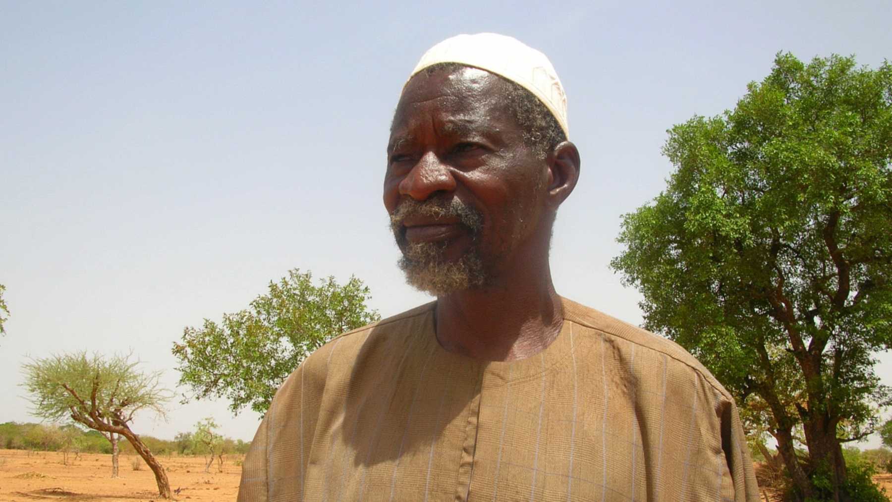 Burkina Faso farmer Yacouba Sawadogo standing in front of trees on his land