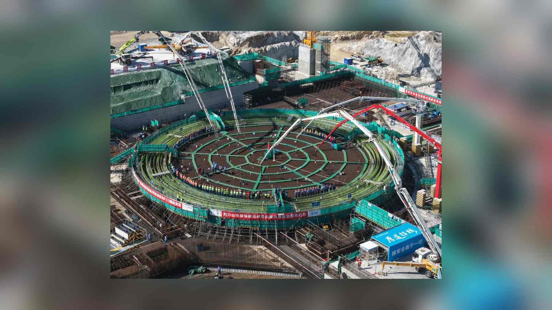 Workers line the rebar grid of the Unit 2 reactor building foundation at the Zhaoyuan nuclear plant as concrete pump booms start the first pour