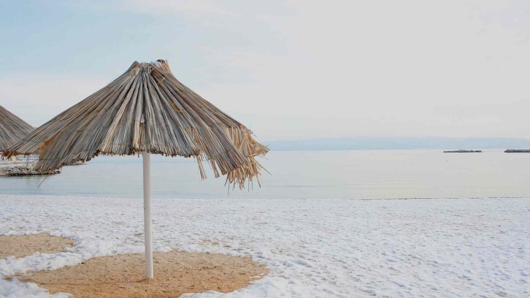 Playa andaluza cubierta de nieve con un parasol, imagen del episodio invernal que ha activado avisos de la AEMET