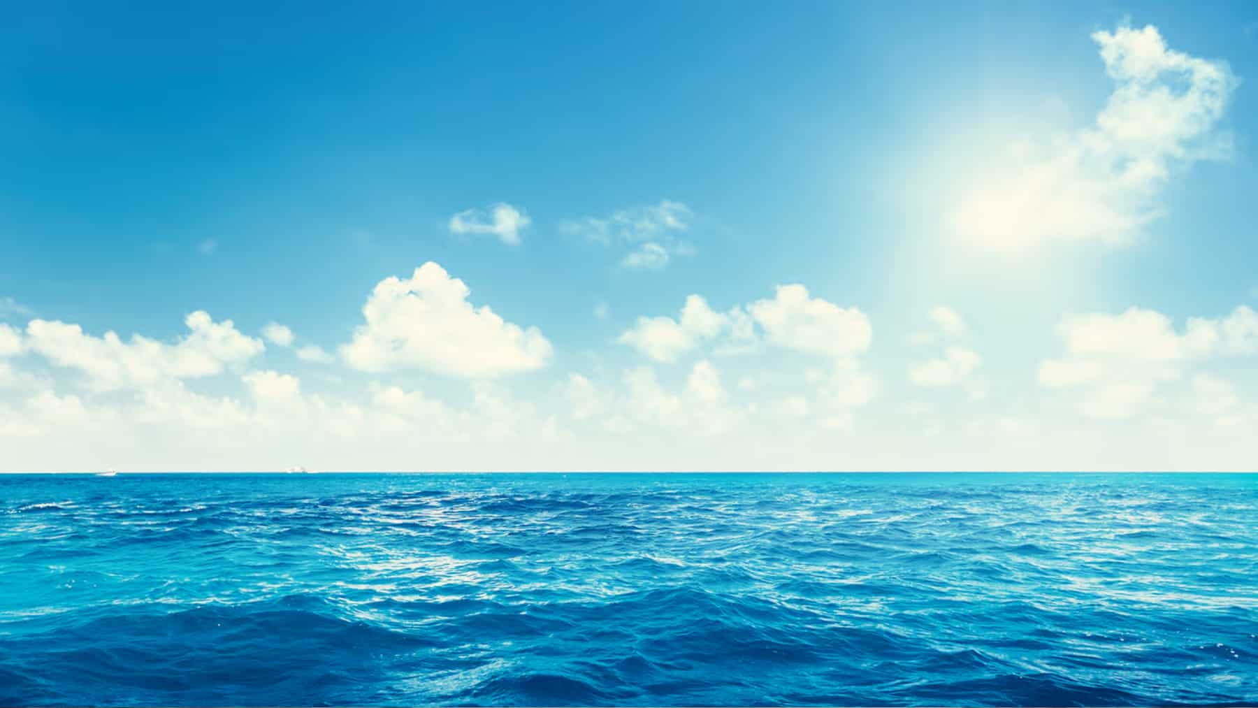 Vista del océano con el mar en calma y el cielo despejado con algunas nubes