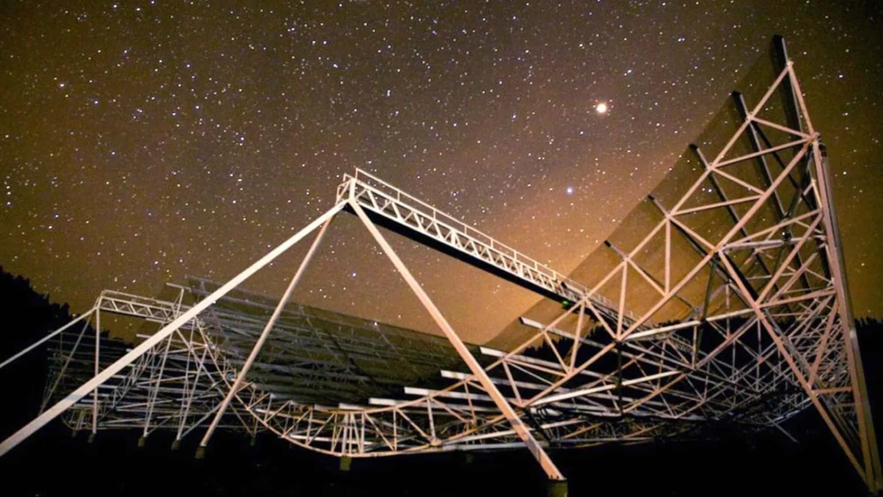 Radiotelescopio bajo un cielo estrellado durante una observación astronómica nocturna