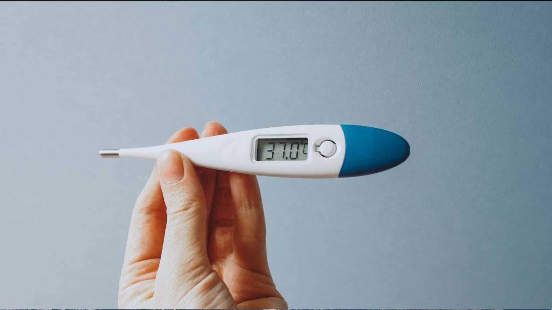 Termómetro digital marcando 37 grados de temperatura corporal sostenido con la mano