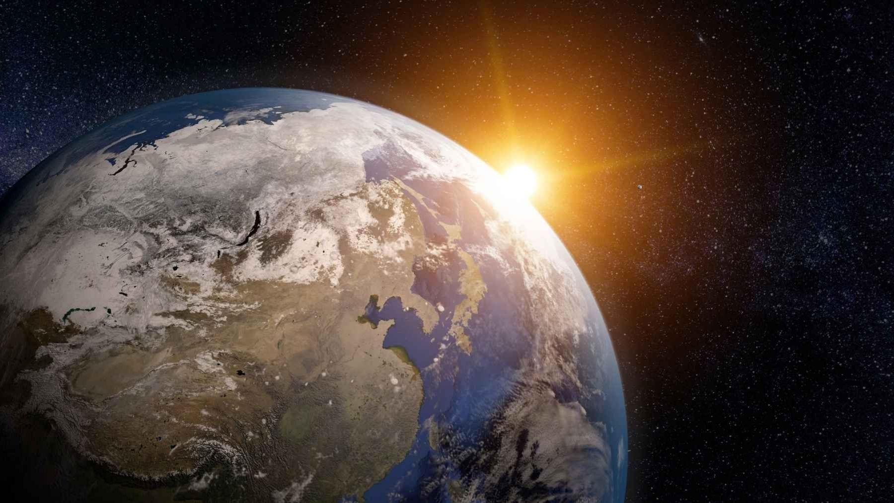 Vista de la Tierra desde el espacio con el sol al fondo representando la gravedad y la teoría del universo como simulación.