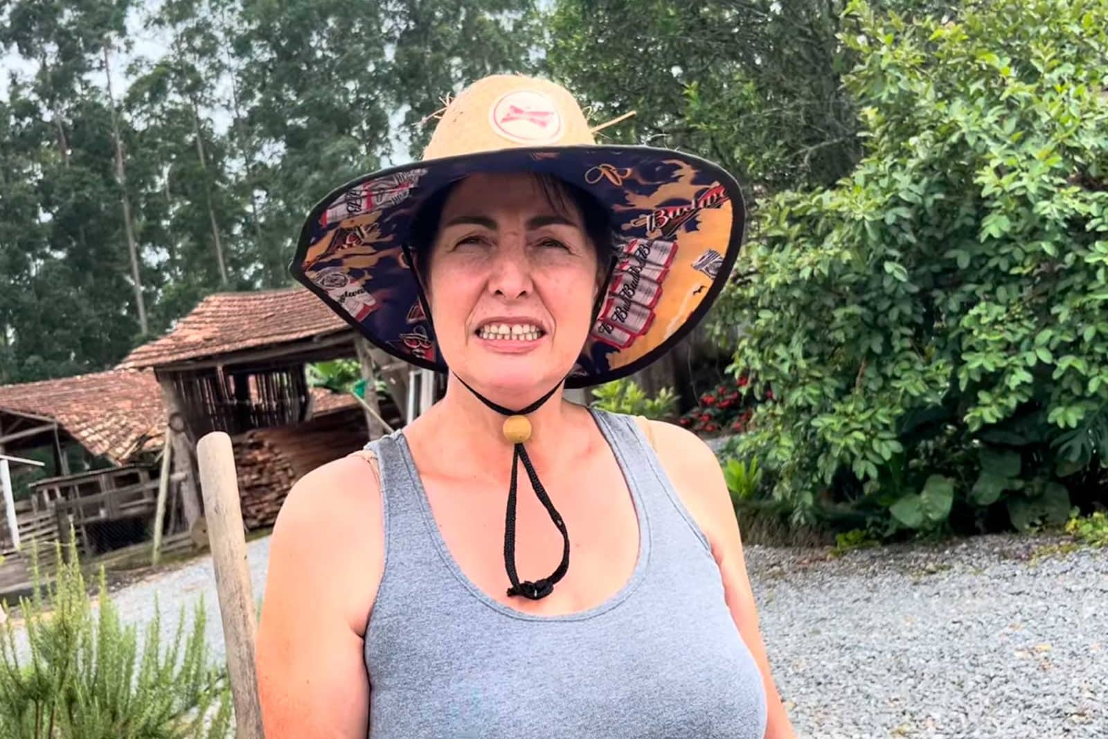 Mujer sonriente con sombrero en un entorno rural al aire libre