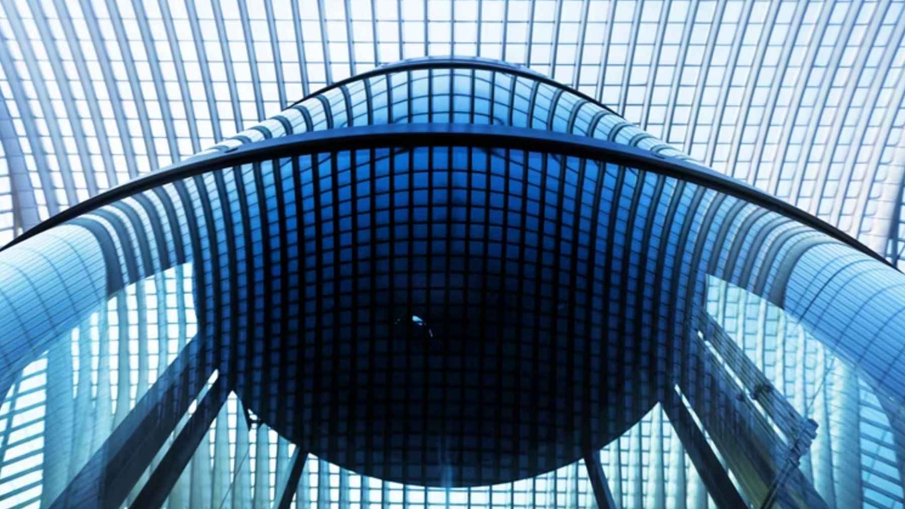 Techo acristalado y estructura metálica azul de un edificio moderno, vista desde abajo