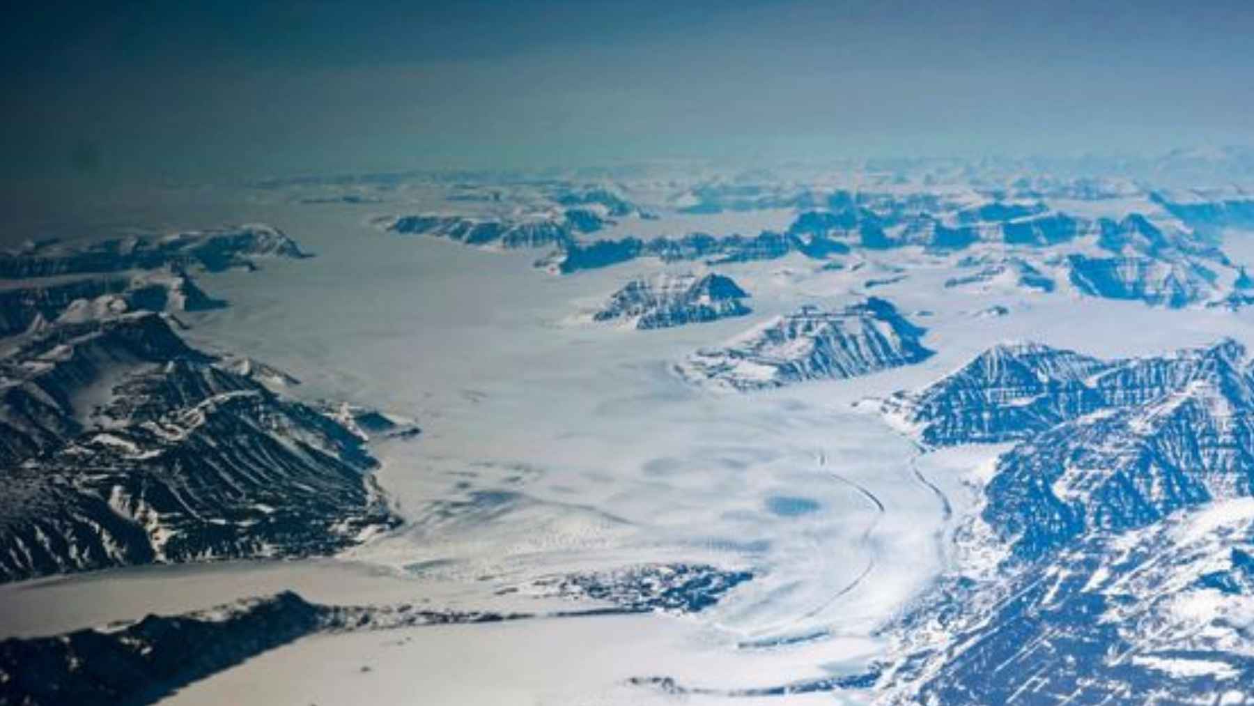 Vista aérea de la capa de hielo de Groenlandia con glaciares y montañas, en el Ártico