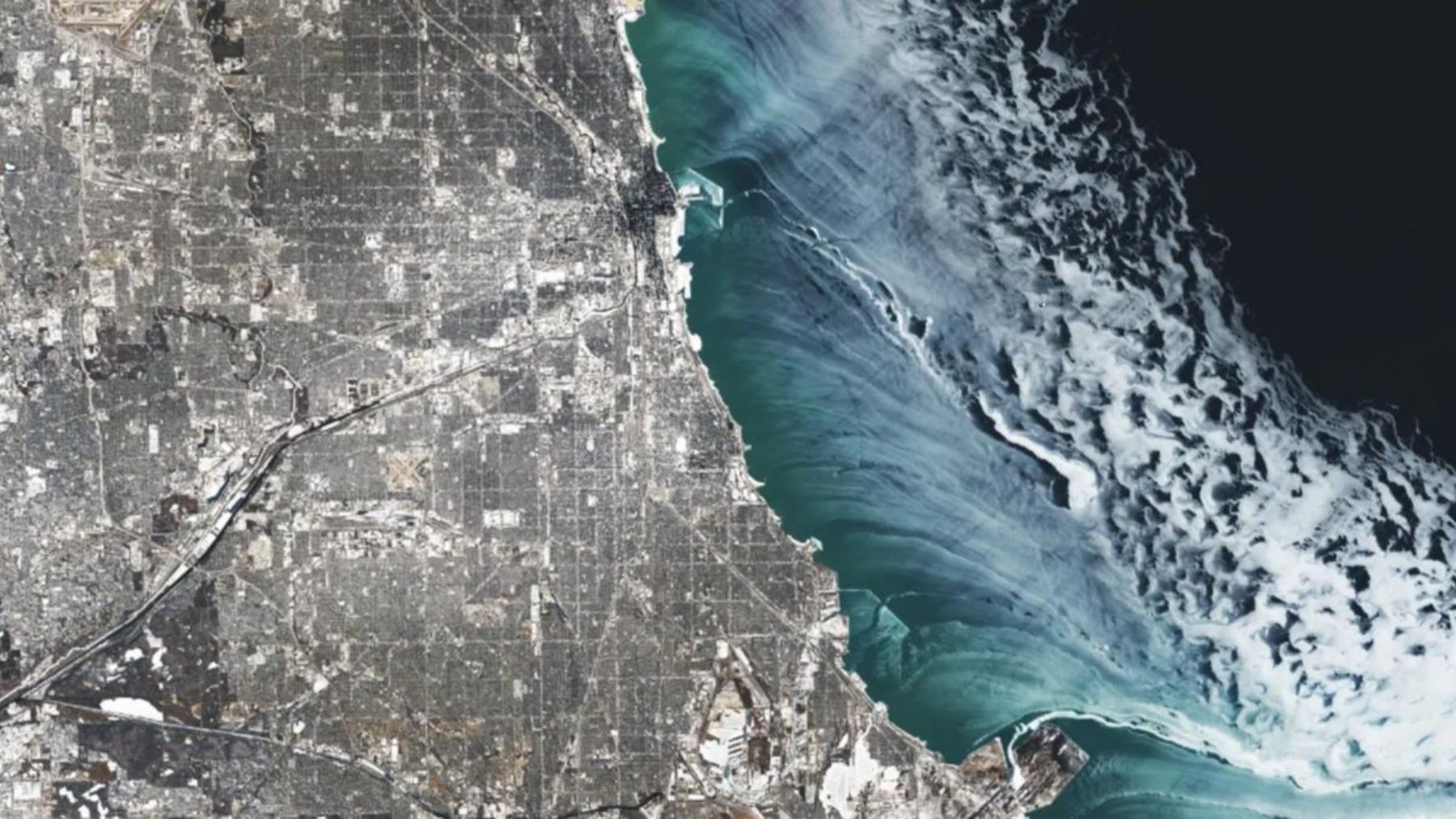 Imagen satelital de cintas de hielo blanco formando remolinos sobre el agua oscura del lago Michigan durante el vórtice polar en Chicago.