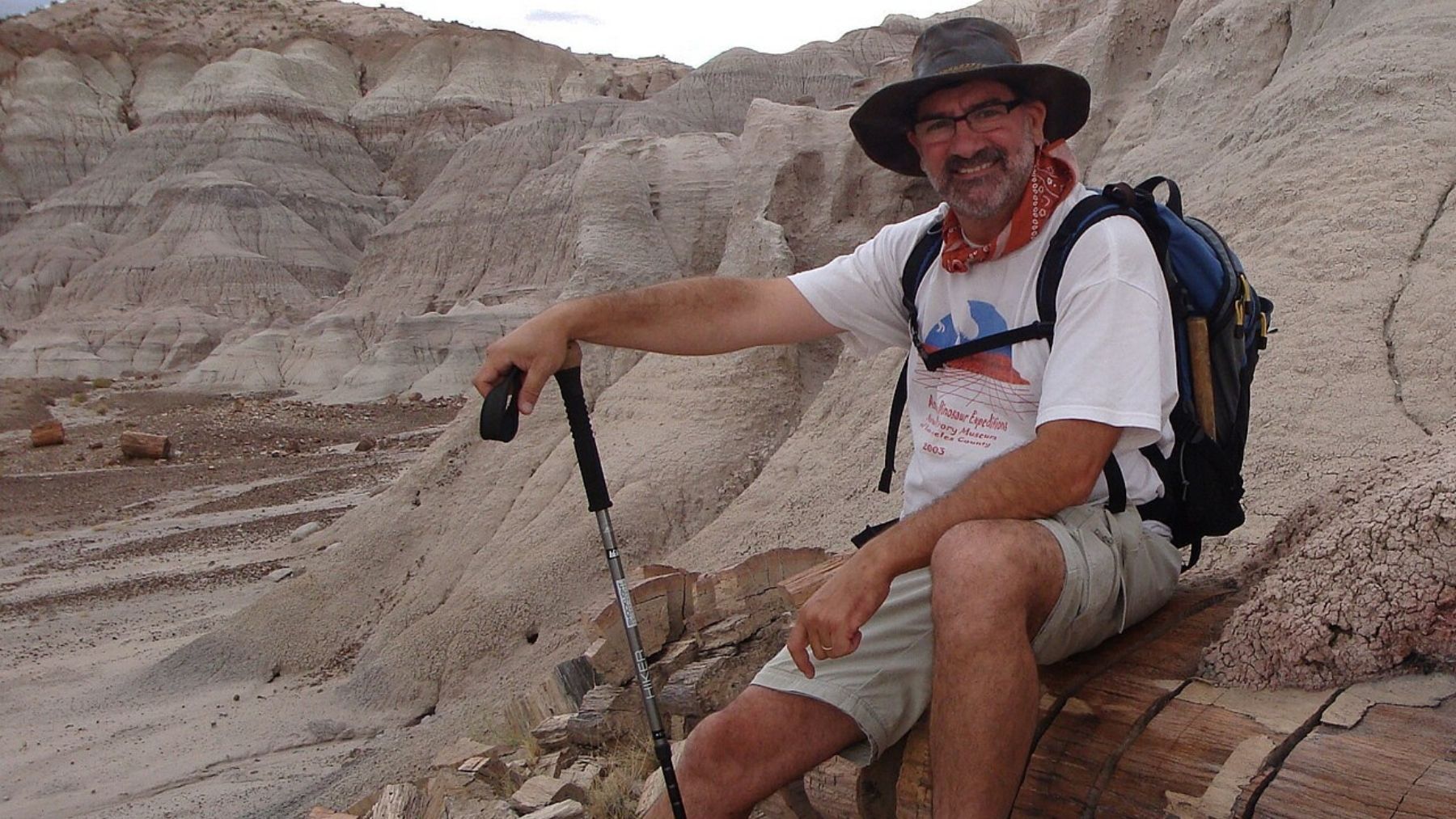 Luis M. Chiappe, paleontólogo y directivo del Museo de Historia Natural de Los Ángeles, sentado sobre troncos petrificados en un yacimiento.