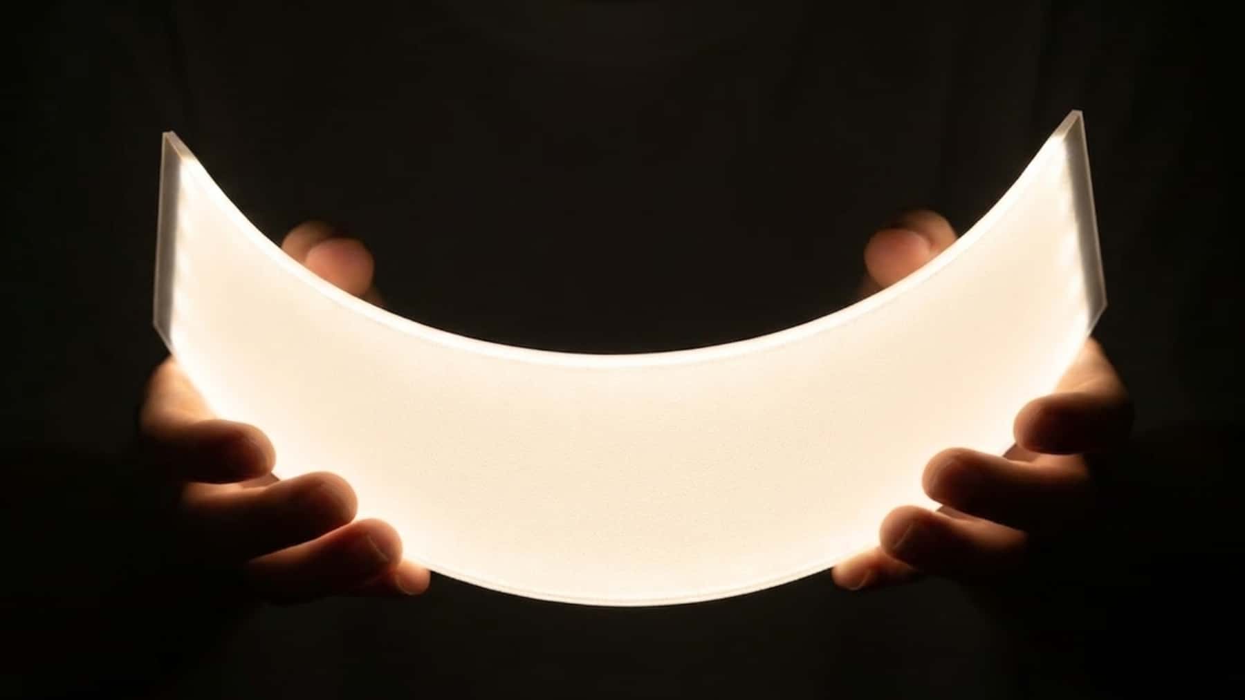 Manos sosteniendo una hoja de papel iluminada en la oscuridad, en primer plano.